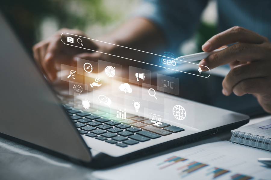 A laptop with several floating icons and the word SEO highlighted